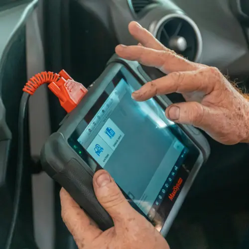 Hand holding a tablet scanning a vehicle's dashboard area