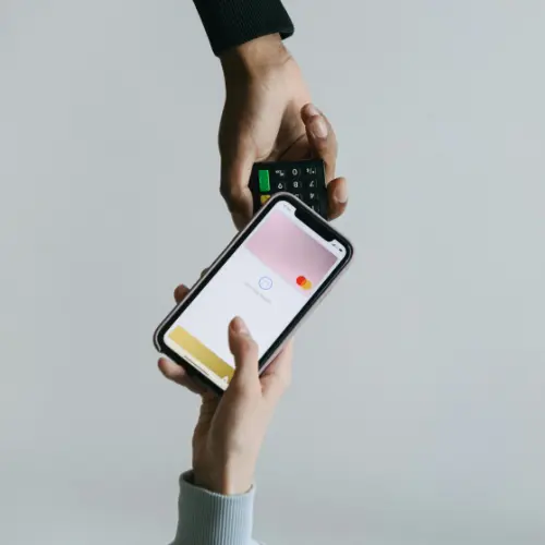 Two hands holding a smartphone and tapping a card reader